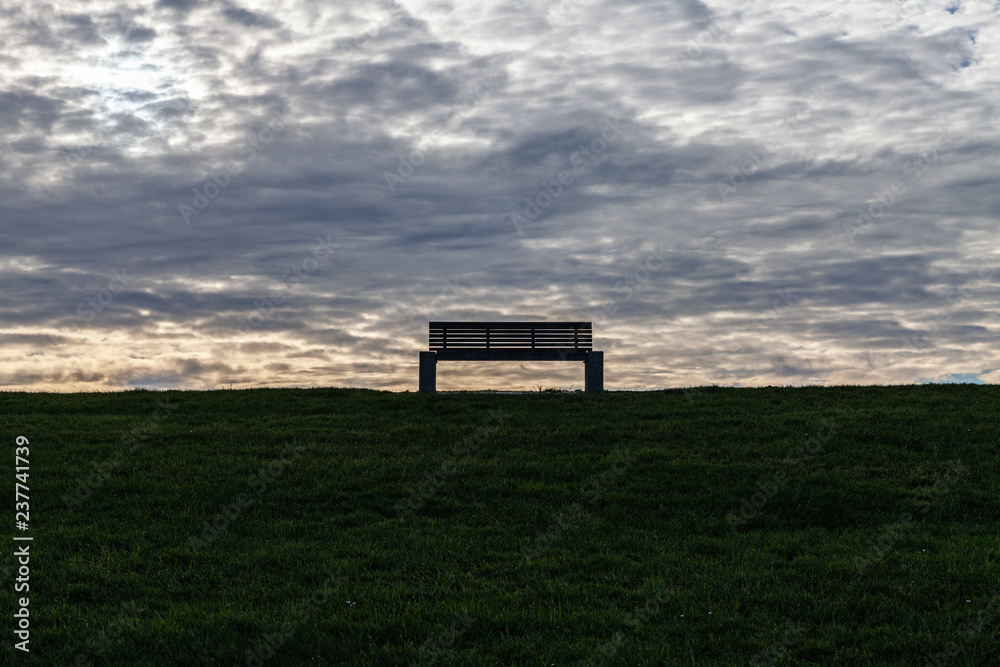 Leere Bank vor wolkigem Himmel Leere Bank vor wolkigem Himmel