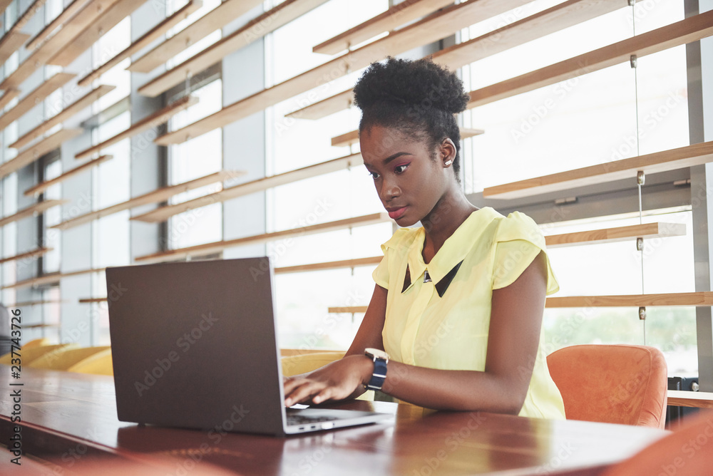 Fototapeta premium Beautiful young woman sitting in a cafe and working on a laptop