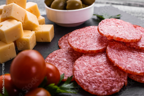 delicious sliced salami on a stone plate wooden background