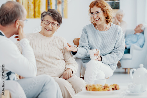 Group of elderly people at senior's club talking and laughing together during meeting