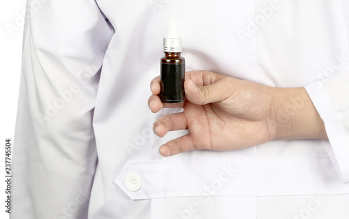 Asian doctor or scientist hand holding spuit, dropping pipet, pipette, medicine, brown glass container eye dropper chemical in the back side of the doctor.