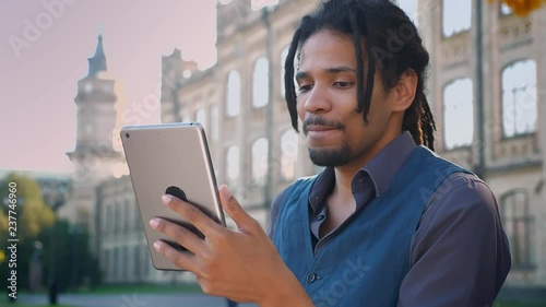 Wallpaper Mural Portrait of attractive African-American student with dreadlocks talking in videochat using tablet on university background. Torontodigital.ca