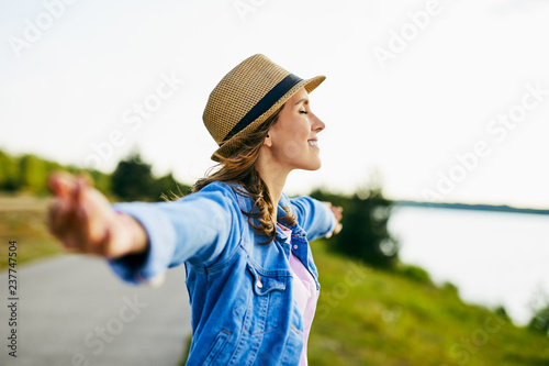 Portrait of young woman stretching her arms with eyes closed enjoying beautiful summer day photo