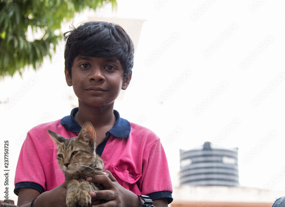 Obraz premium Young Indian boy holding kitten in his hand
