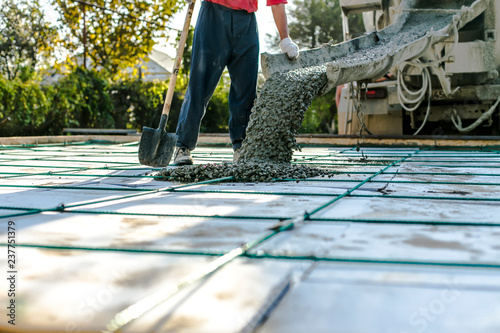 Mixer track pouring wet cement to the civil building foundation. Construction workers in the process of forming house concrete slab at the construction site.