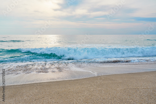 Waves with foam hitting sand on the tropical beach texture. © Arthur