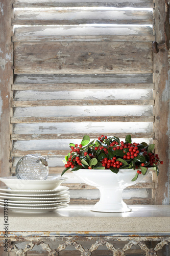 Christmas holly in dish and stack of plates