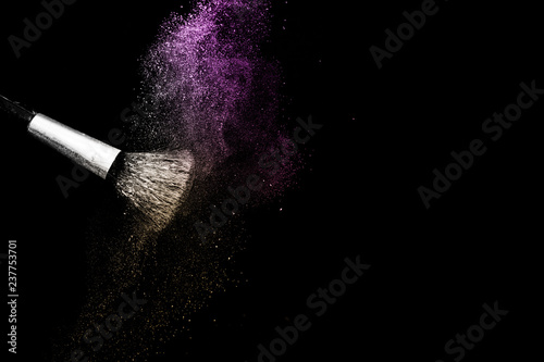 gold and purple powder splash and brush for makeup artist or beauty blogger in black background