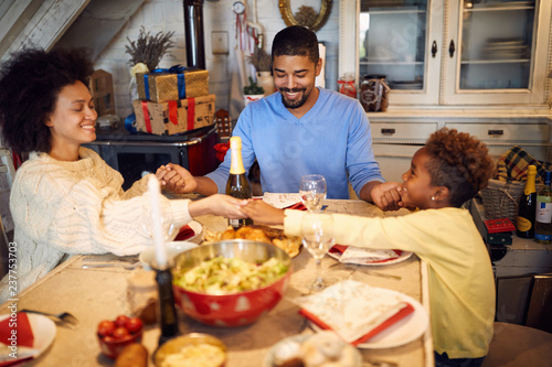 holidays and celebration concept - happy family having Christmas prayer for dinner at home.