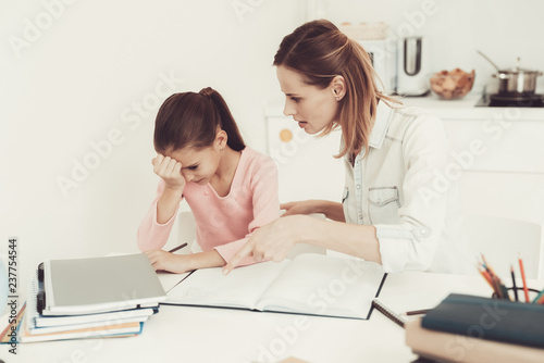 Mom Helps Daughter To Do Homework In The Kitchen.