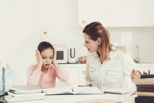 Mom Helps Daughter To Do Homework In The Kitchen.