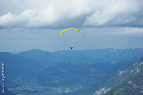 single yellow paraplane flies over the Austrian Alps under stormy clouds. Region Dachstein in the Austrian state of Styria
