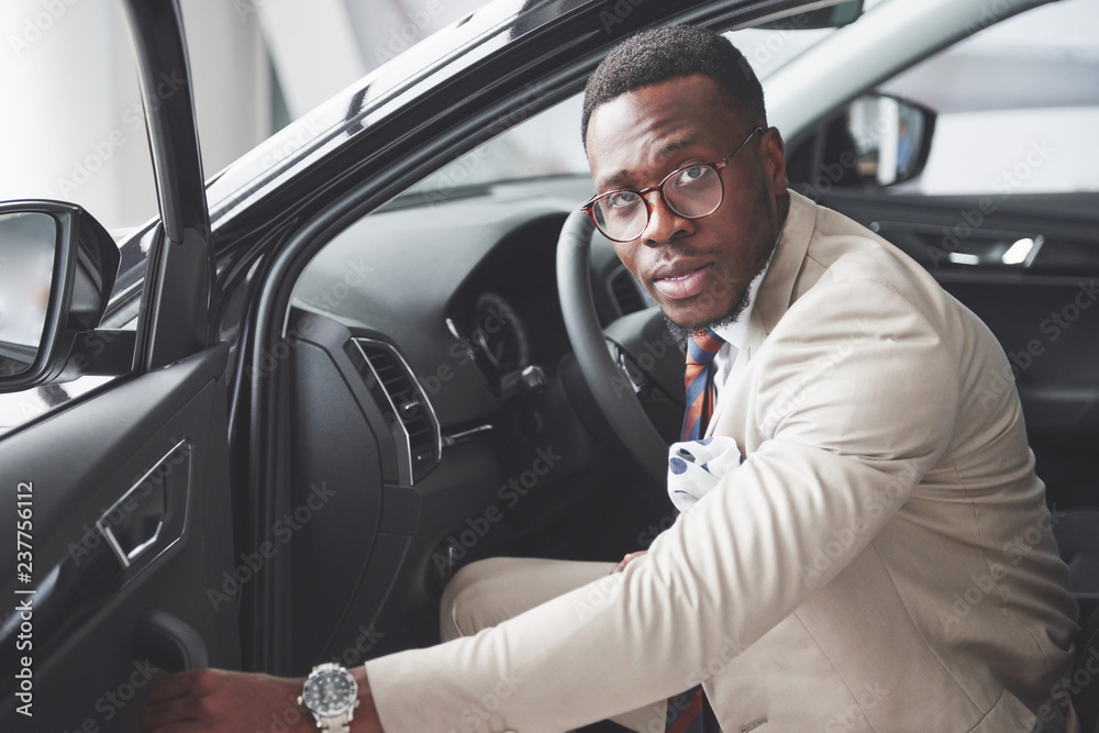 Stylish black businessman sitting behind the wheel of new luxury car. Rich african american man Stylish black businessman sitting behind the wheel of new luxury car. Rich african american man