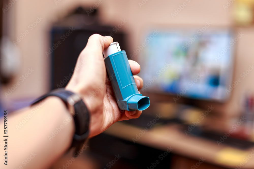 Caucasian man with asthma spray in hand at the office.