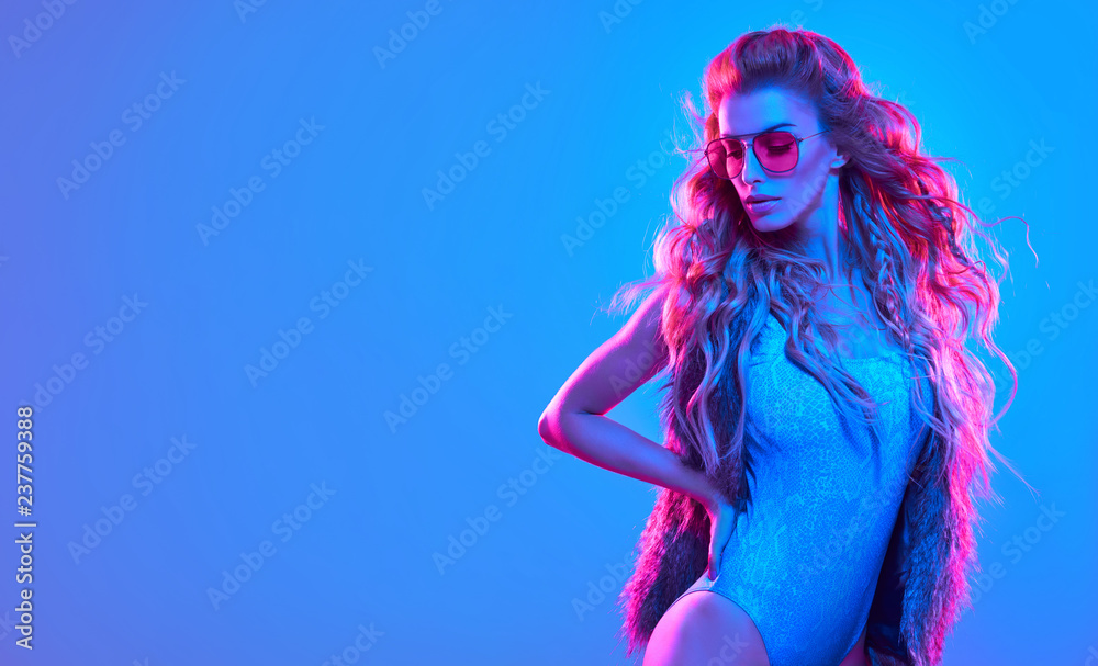 Fototapeta Fashionable glamour beautiful woman with Trendy wavy neon light hairstyle. Party night club vibes, gel filter. Excited shapely sexy girl. Bright pink blue lighting. Art fashion creative neon color.