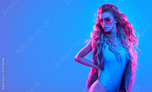 Fashionable glamour beautiful woman with Trendy wavy neon light hairstyle. Party night club vibes, gel filter. Excited shapely sexy girl. Bright pink blue lighting. Art fashion creative neon color.