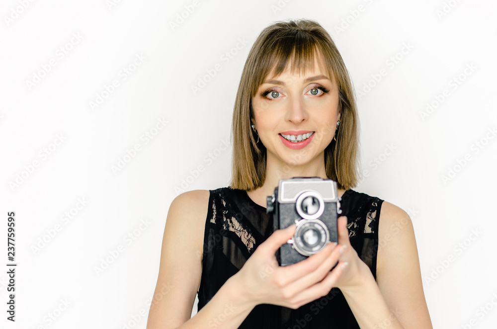 Fototapeta premium Portrait smiling young woman fashion look pretty cool model with retro film camera wearing elegant black dress white background