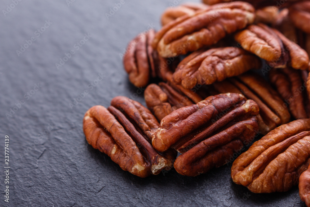 delicious pecan nuts on a dark stone background delicious pecan nuts on a dark stone background