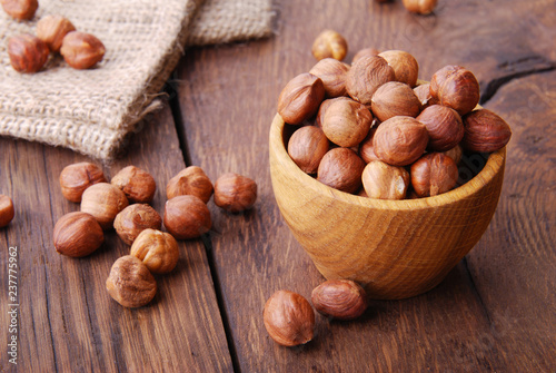 Raw hazelnut in a bowl on a dark wooden background.