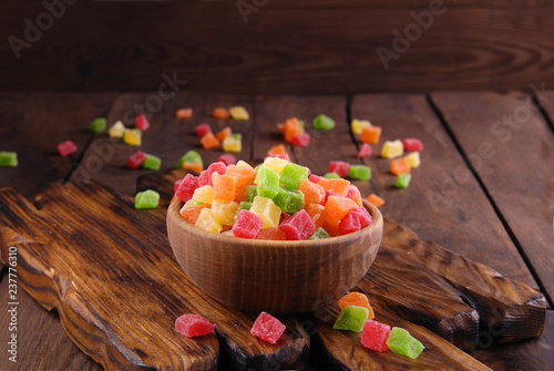 Multicolored dry fruits in a bowl on a wooden table.
