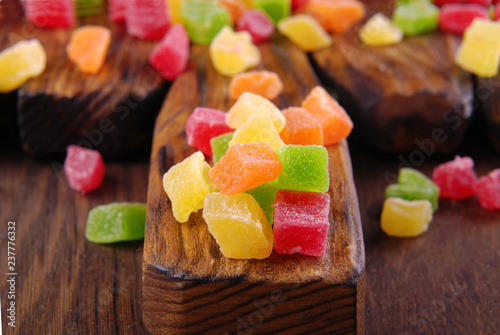 Multicolored dry fruits in a bowl on a wooden table.
