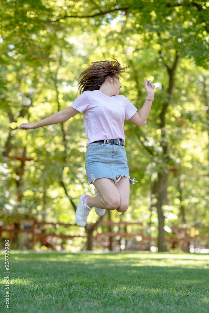 Beautiful teen girl Is jumping outside at summer sunset.Girl dancer doing a beautiful jumping movement on green grass Beautiful teen girl Is jumping outside at summer sunset.Girl dancer doing a beautiful jumping movement on green grass