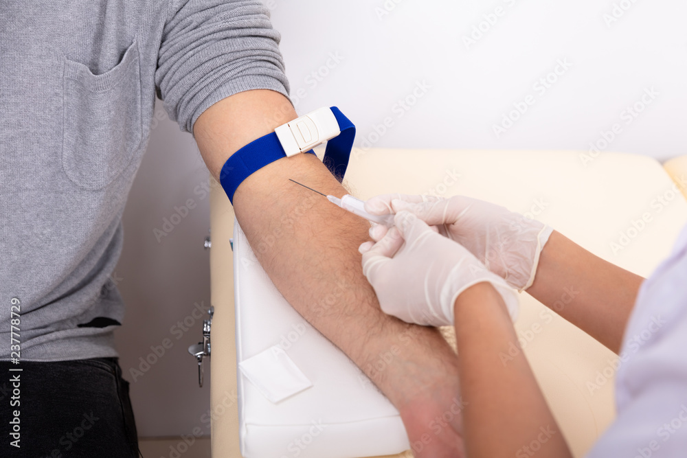 Obraz premium Doctor Injecting Patient With Syringe To Collect Blood