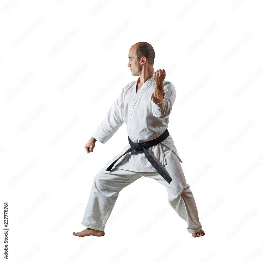 Black belt athlete doing formal karate exercises on a white isolated background