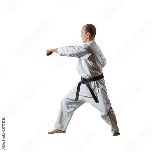 Black belt athlete trains formal karate exercises on white isolated background
