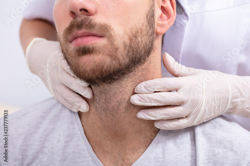 Doctor Performing Physical Exam Palpation Of The Thyroid Gland photo