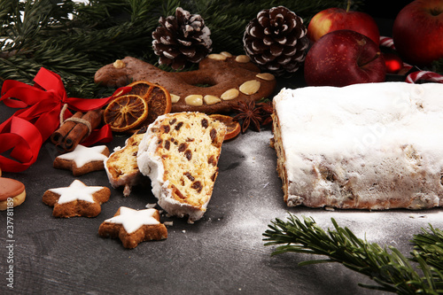 Traditional European Christmas pastry, fragrant home baked stollen, with spices and dried fruit. Sliced on rustic table with xmas tree branches and decorations