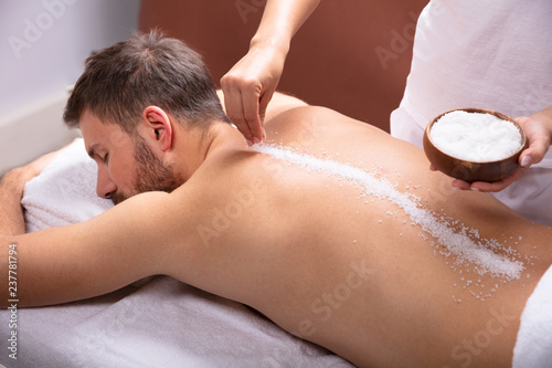 Therapist Applying Salt On Man's Back