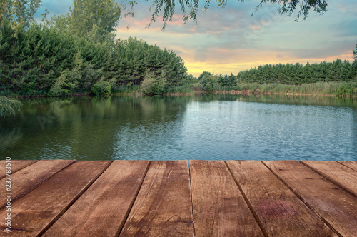 Wooden table perspective and a river landscape in background. Sunny summer day.