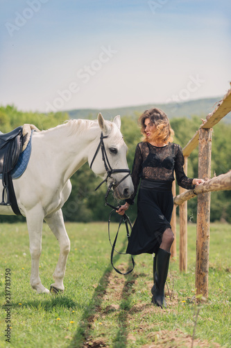 Young woman in black dress with her white horse outdoor