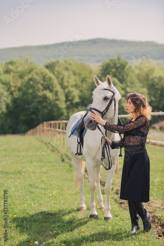 Young woman in black dress with her white horse outdoor © chrisgraphics