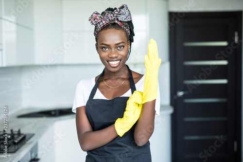 Cheerful african woman wearing rubber gloves standing in the kitchen