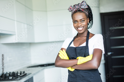 Young african woman with arms crossed before cleaning in the kitchen photo