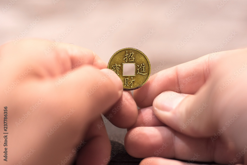 Close up capture of an Caucasian man hands holding and old feng shui coin. Lucky Chinese Fortune new years cake coin. Close up capture of an Caucasian man hands holding and old feng shui coin. Lucky Chinese Fortune new years cake coin.
