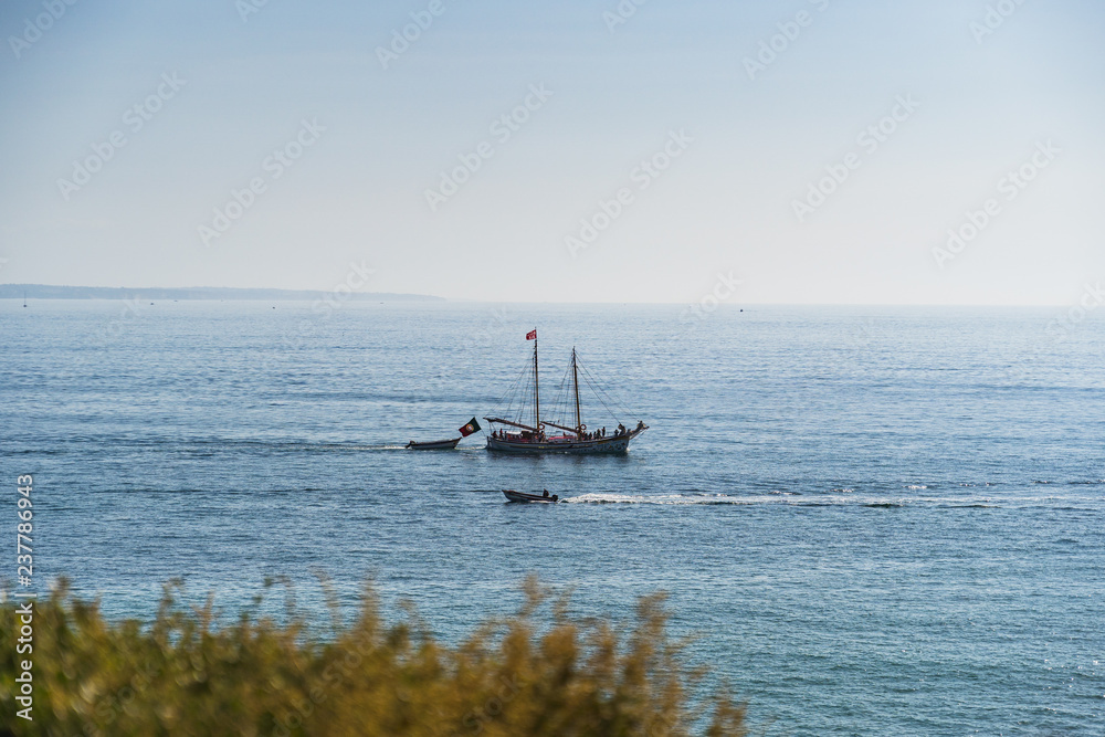 Sailboat passing dingy