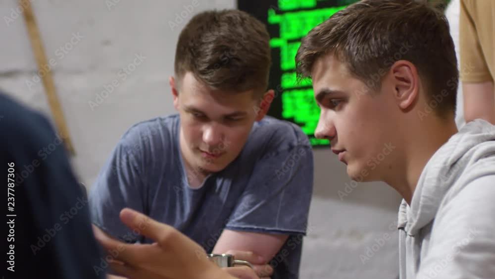 Medium shot of young Caucasian man discussing task with friend or groupmate during programming workshop Medium shot of young Caucasian man discussing task with friend or groupmate during programming workshop
