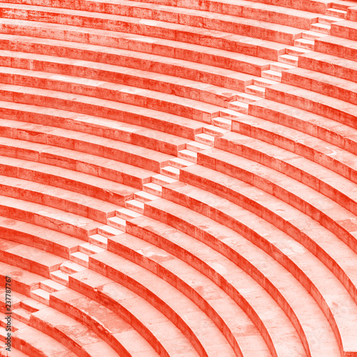 Old amphitheatre steps close up texture. Living coral colors. photo