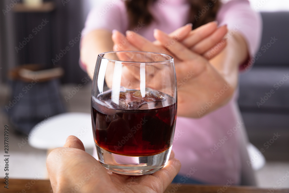 Woman Refusing Glass Of Drink Offered By Person
