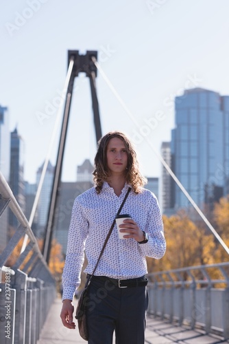 Man holding coffee cup on the bridge in the city photo