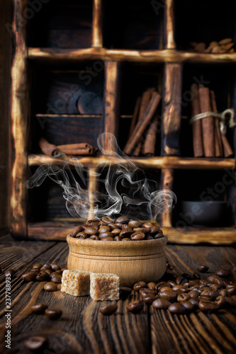 Hot steaming coffee beans in bowl on rustic wooden background