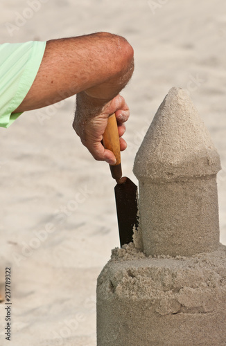 Back view, long distance of a middle aged mans arem and hand, sculpting a sand castle on a sandy, tropical beach on the gulf of mexico on a sunny, winter afternoon photo