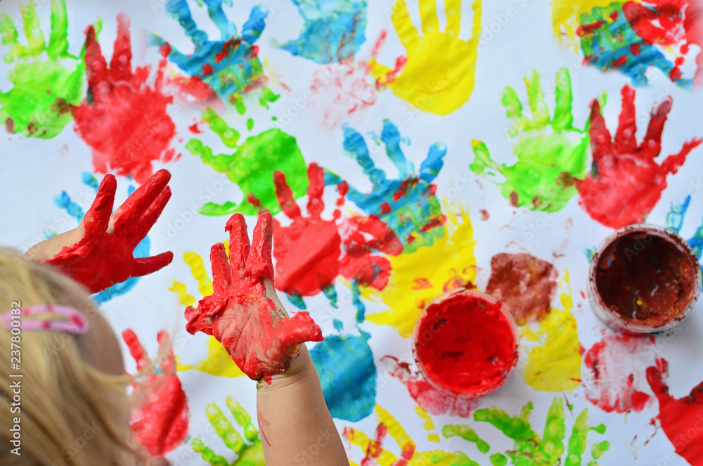 Painted hands of little girl in red colour during the play