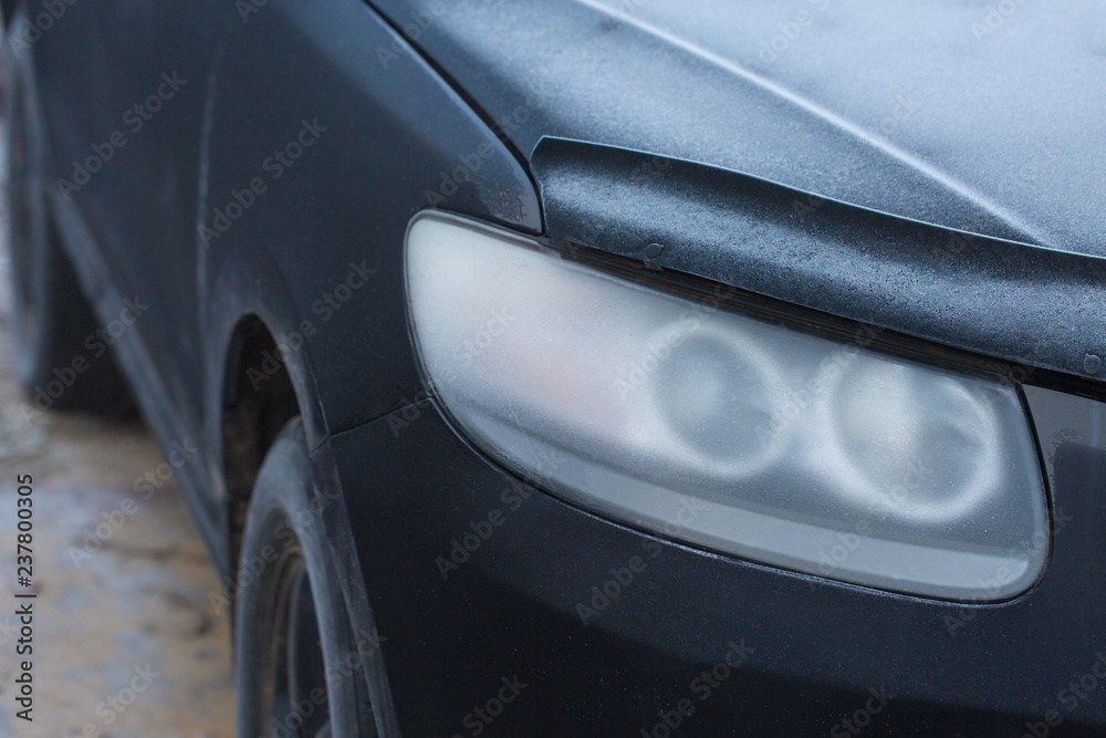 The headlight of the car is covered with hoarfrost