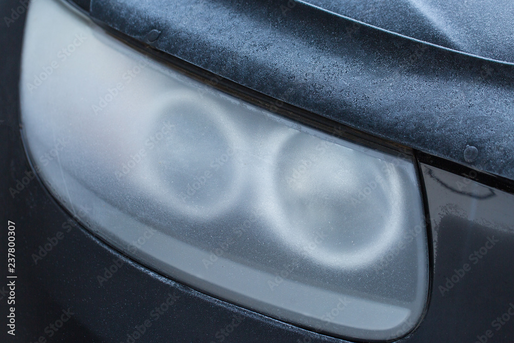 The headlight of the car is covered with hoarfrost