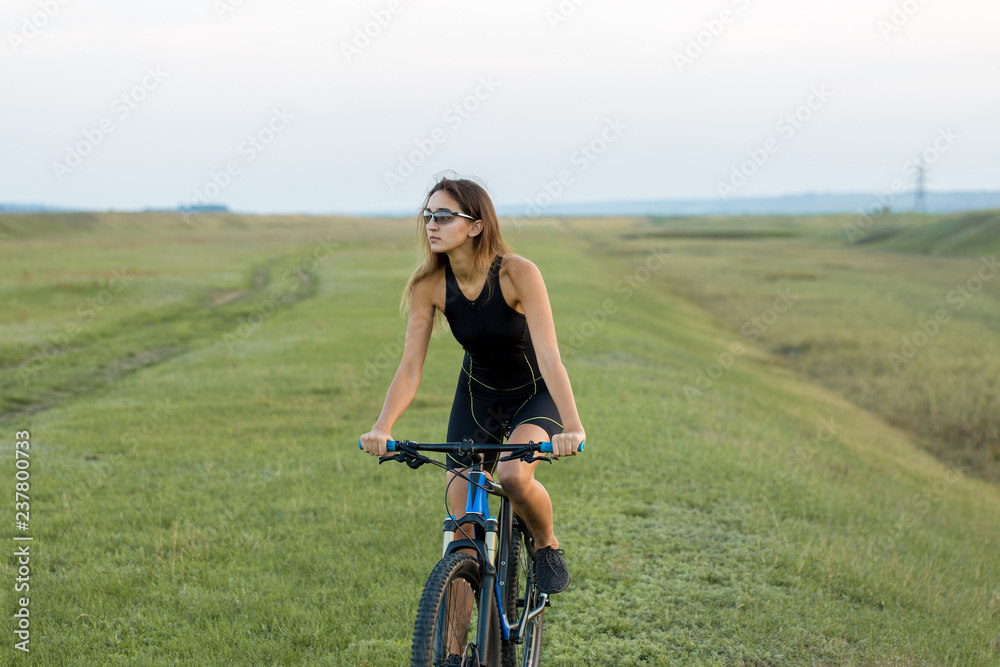 A girl riding a mountain bike on an asphalt road, beautiful portrait of a cyclist at sunset A girl riding a mountain bike on an asphalt road, beautiful portrait of a cyclist at sunset