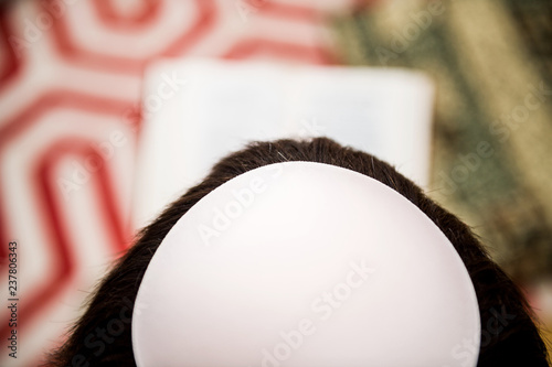 Focus on the Kippah of a Jewish male reading Bi-lingual Hebrew French mahzor prayer book from 1920 used on the High Holy Days of Rosh Hashanah and Yom Kippur photo